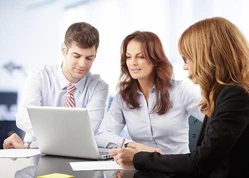 Agents sitting at table looking at laptop